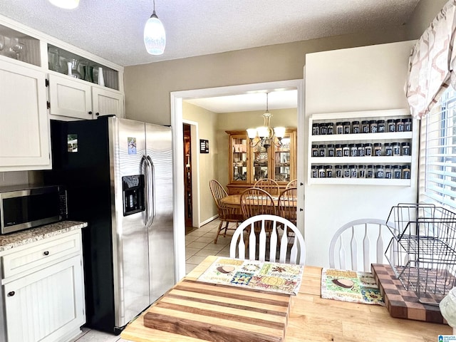 kitchen with white cabinetry, hanging light fixtures, a chandelier, and appliances with stainless steel finishes