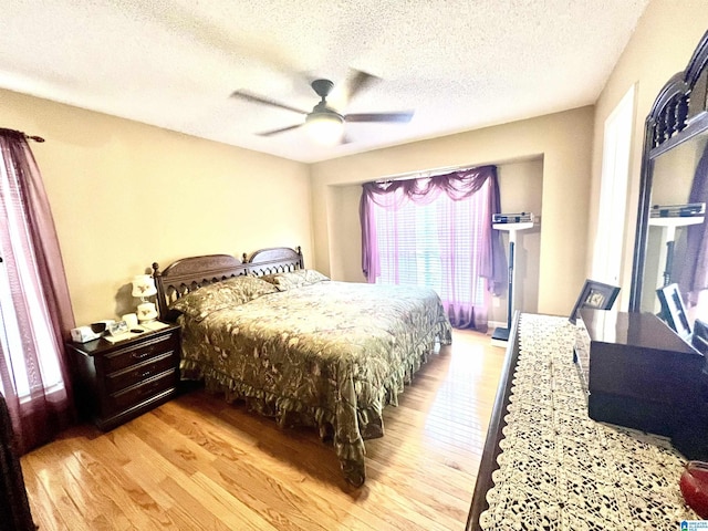 bedroom with ceiling fan, a textured ceiling, and light wood-type flooring