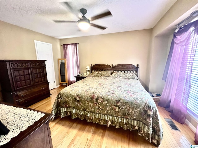 bedroom with ceiling fan, a textured ceiling, and light hardwood / wood-style floors