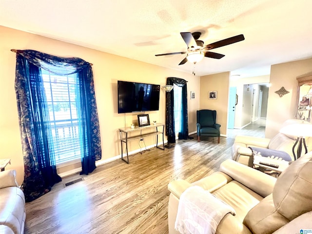 living room featuring ceiling fan, wood-type flooring, and a textured ceiling