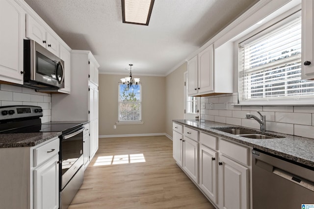 kitchen with white cabinetry, appliances with stainless steel finishes, decorative light fixtures, and sink