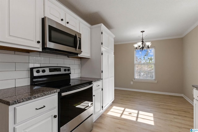 kitchen with appliances with stainless steel finishes, backsplash, ornamental molding, white cabinets, and decorative light fixtures