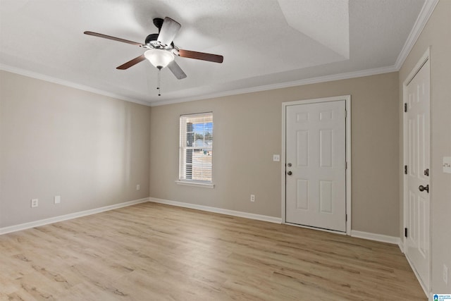 empty room featuring ceiling fan, a raised ceiling, crown molding, a textured ceiling, and light hardwood / wood-style flooring