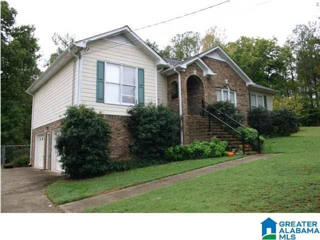 single story home with a garage, driveway, brick siding, stairway, and a front yard