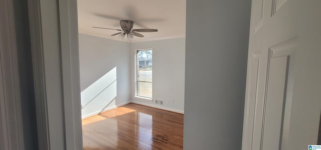 empty room with ornamental molding, ceiling fan, and light wood-type flooring