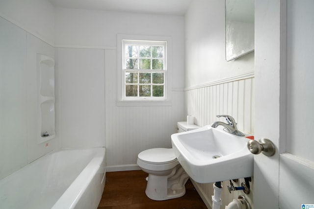 bathroom featuring a tub to relax in, hardwood / wood-style floors, sink, and toilet