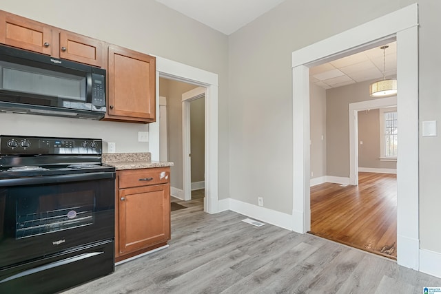 kitchen featuring a paneled ceiling, light hardwood / wood-style floors, and black appliances