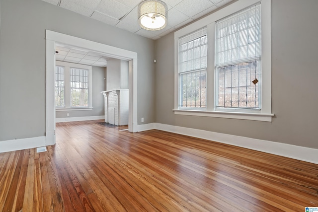 unfurnished living room with hardwood / wood-style floors and a paneled ceiling