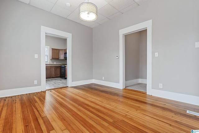 unfurnished room featuring light hardwood / wood-style flooring and a drop ceiling