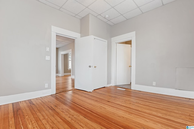 empty room with a paneled ceiling and light hardwood / wood-style flooring