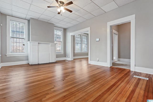 empty room featuring ceiling fan, light wood-type flooring, and a drop ceiling