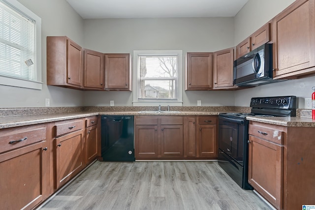 kitchen featuring sink, light wood-type flooring, and black appliances