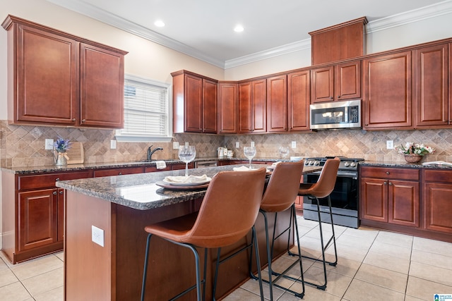 kitchen with stainless steel appliances, dark stone countertops, a center island, and light tile patterned floors