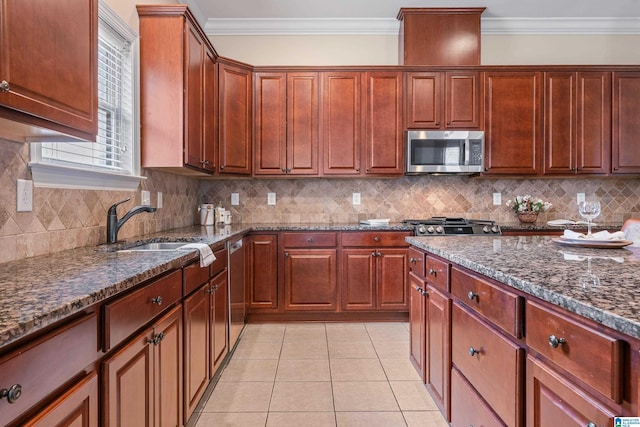 kitchen with ornamental molding, dark stone counters, sink, and light tile patterned floors