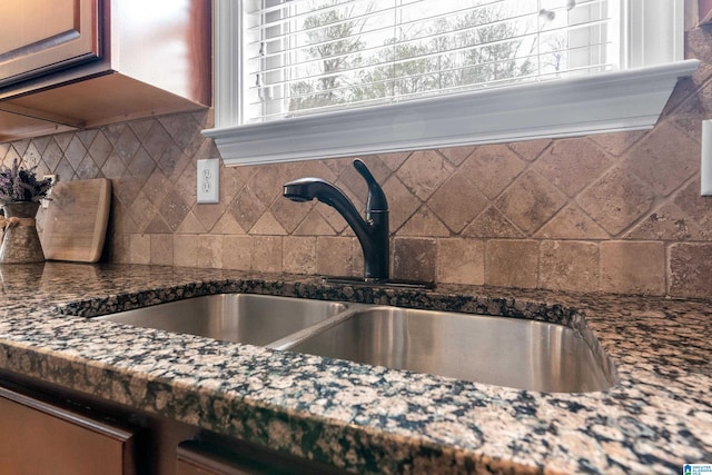 interior details with sink, backsplash, and dark stone counters