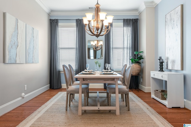 dining area with crown molding, wood-type flooring, and a chandelier