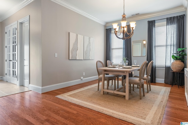 dining area with hardwood / wood-style flooring, ornamental molding, and a chandelier