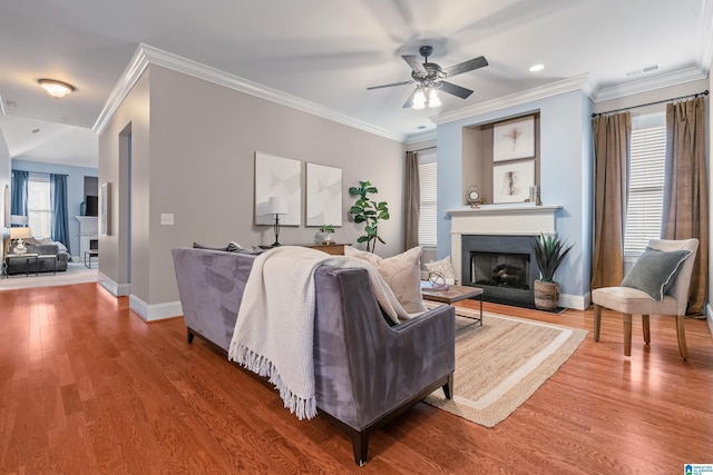 living room with wood-type flooring, ornamental molding, and ceiling fan