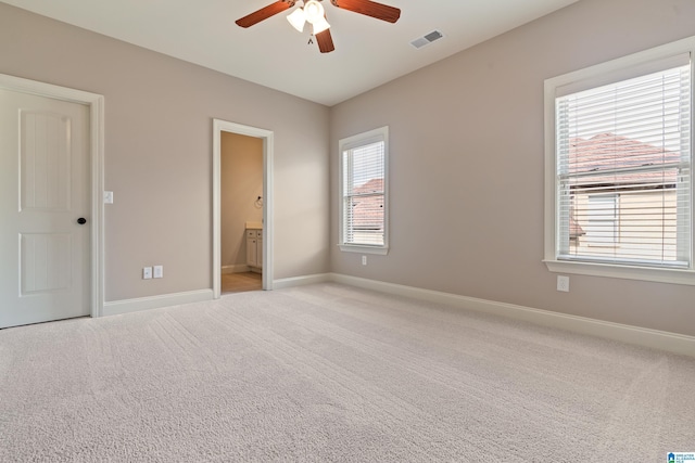 unfurnished bedroom with ceiling fan, light colored carpet, and ensuite bathroom