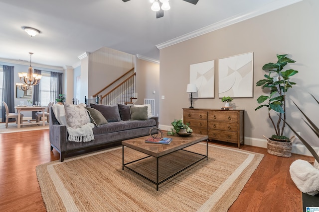 living room featuring crown molding, wood-type flooring, and ceiling fan with notable chandelier