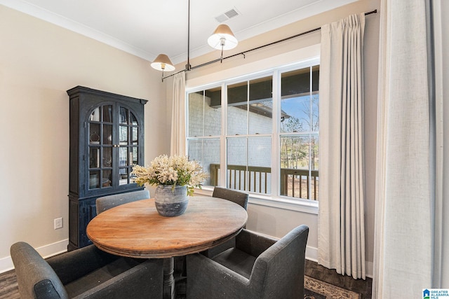 dining space featuring dark wood-style floors, baseboards, visible vents, and ornamental molding