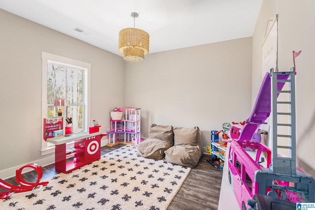 game room with an inviting chandelier, wood finished floors, visible vents, and baseboards