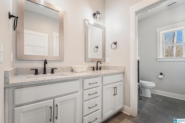 full bathroom with visible vents, a sink, toilet, and double vanity