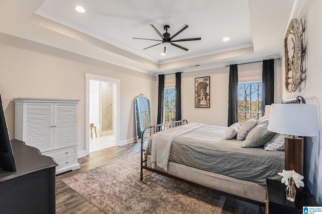 bedroom featuring baseboards, ornamental molding, dark wood-style flooring, a tray ceiling, and recessed lighting