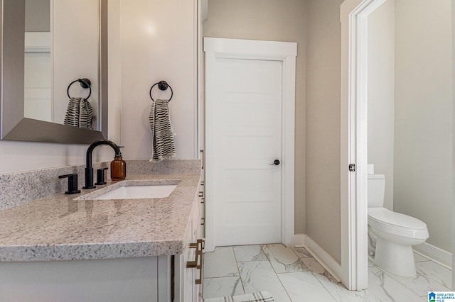 bathroom with toilet, marble finish floor, and baseboards