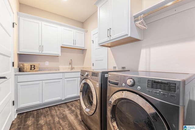 clothes washing area featuring dark wood-type flooring, washing machine and dryer, cabinet space, and a sink