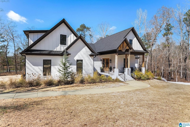 modern farmhouse style home with board and batten siding, covered porch, brick siding, and roof with shingles