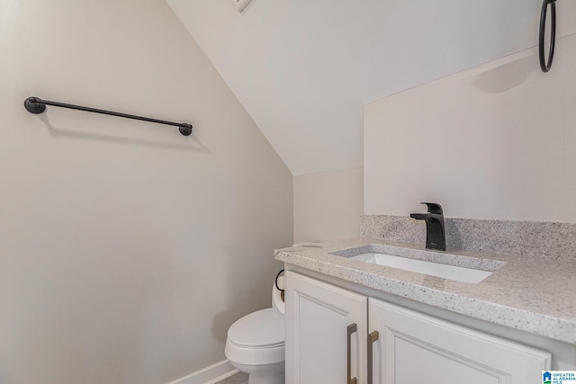 bathroom with baseboards, vaulted ceiling, vanity, and toilet