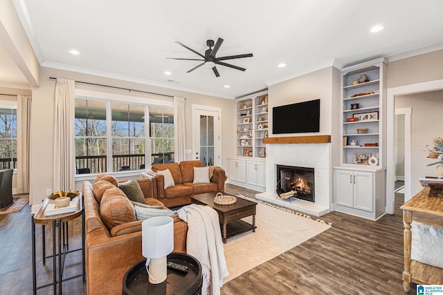 living area featuring a warm lit fireplace, dark wood finished floors, a ceiling fan, and a healthy amount of sunlight