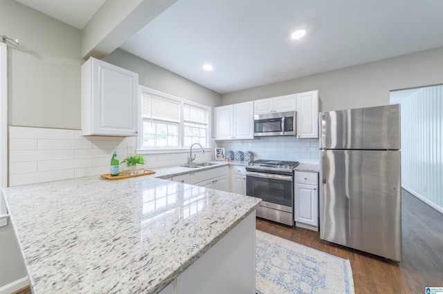 kitchen featuring stainless steel appliances, light stone countertops, sink, and white cabinets