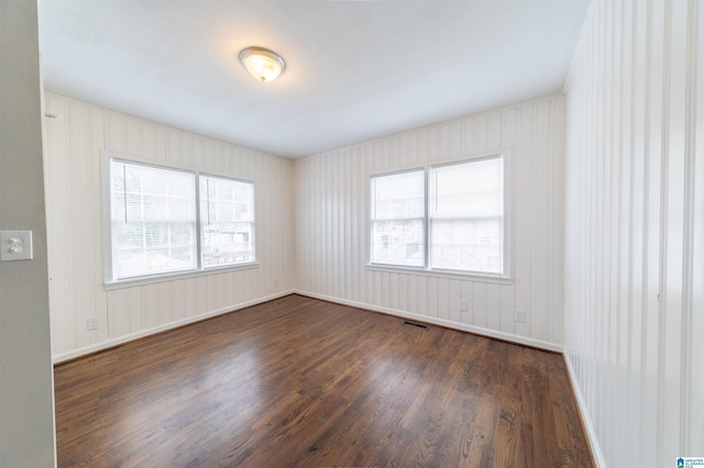 empty room featuring dark hardwood / wood-style flooring and a wealth of natural light