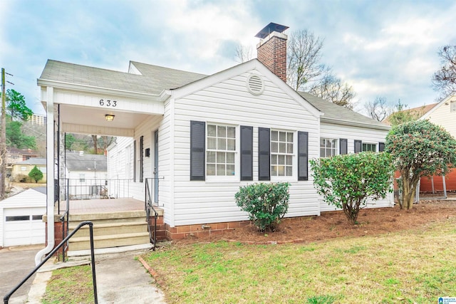 view of front of property featuring a garage, an outbuilding, a front yard, and covered porch