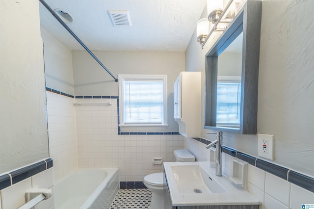 bathroom featuring tile patterned floors, toilet, sink, and tile walls