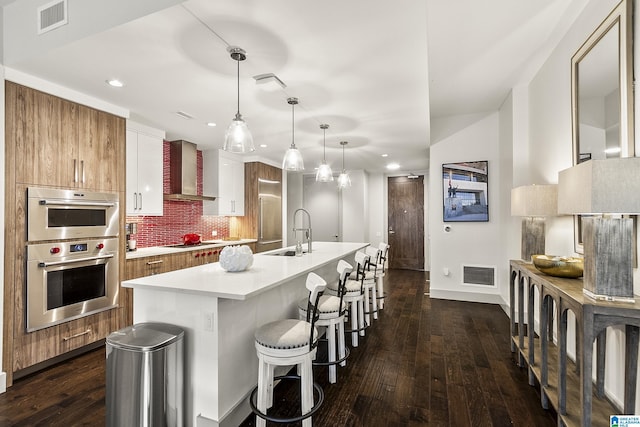 1150 8th St Unit 503, Tuscaloosa, AL 35401 - kitchen featuring sink, electric cooktop, an island with sink, pendant lighting, and wall chimney range hood