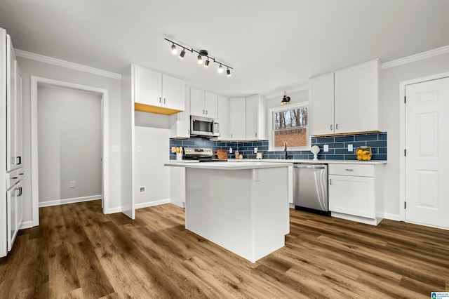 kitchen featuring crown molding, appliances with stainless steel finishes, dark hardwood / wood-style flooring, a kitchen island, and white cabinets