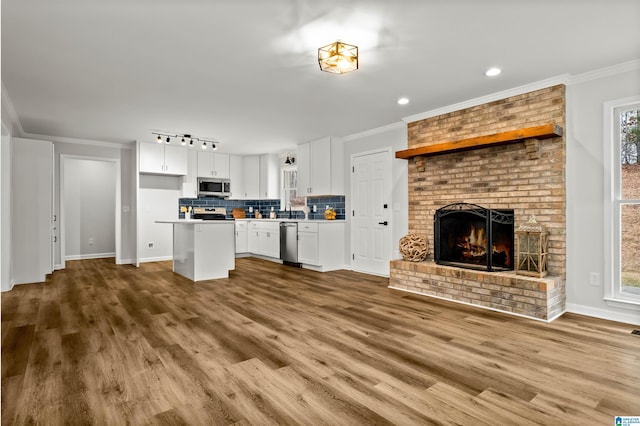 kitchen with white cabinetry, crown molding, a kitchen island, and appliances with stainless steel finishes