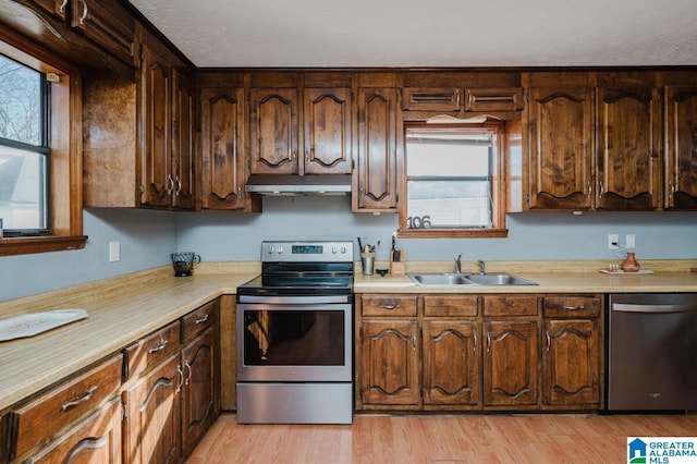 kitchen with sink, stainless steel appliances, a textured ceiling, and light wood-type flooring