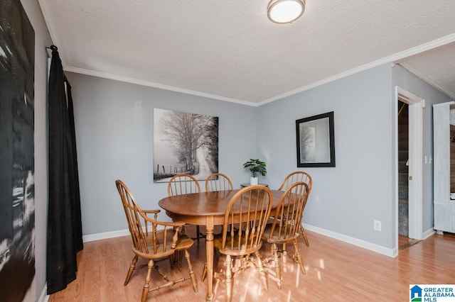 dining room with ornamental molding, light hardwood / wood-style flooring, and a textured ceiling