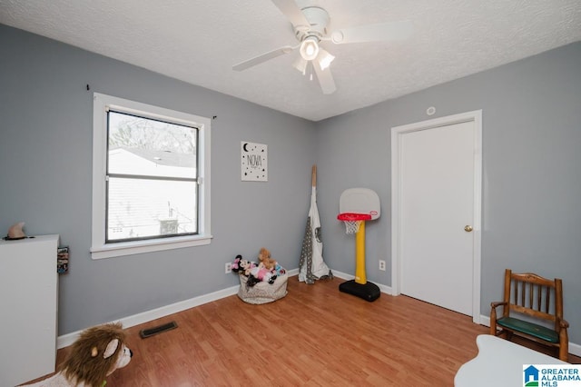 miscellaneous room with ceiling fan, a textured ceiling, and light wood-type flooring