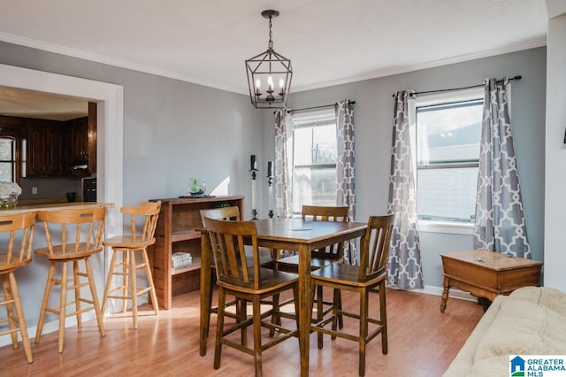 dining area featuring ornamental molding, a chandelier, and light hardwood / wood-style flooring