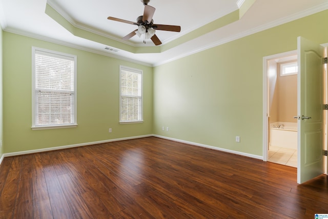 empty room with crown molding, dark hardwood / wood-style floors, and a raised ceiling