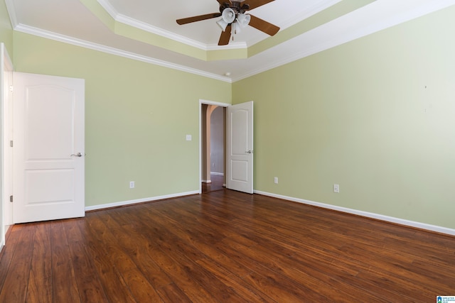 empty room featuring crown molding, ceiling fan, dark hardwood / wood-style flooring, and a raised ceiling