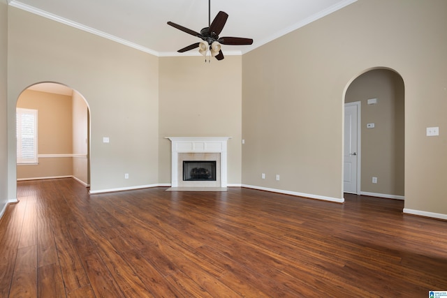 unfurnished living room with ceiling fan, ornamental molding, dark hardwood / wood-style floors, and a tiled fireplace