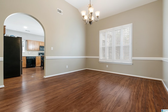 spare room featuring a healthy amount of sunlight, dark wood-type flooring, and an inviting chandelier