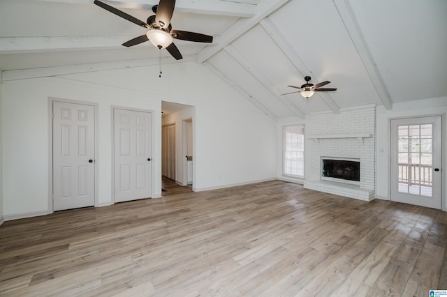 unfurnished living room with plenty of natural light, a fireplace, light wood-type flooring, and vaulted ceiling with beams