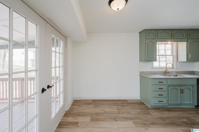 kitchen featuring sink, green cabinets, tasteful backsplash, light hardwood / wood-style floors, and french doors